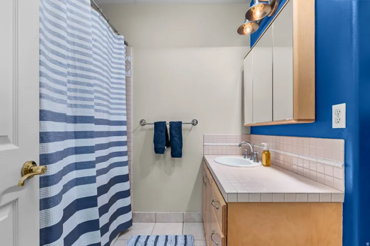 Bathroom featuring a wood-finish vanity with an integrated sink and tile countertop