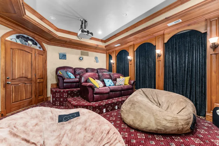 Home theater featuring a ceiling-mounted projector, tiered seating platforms, and rich wood paneling