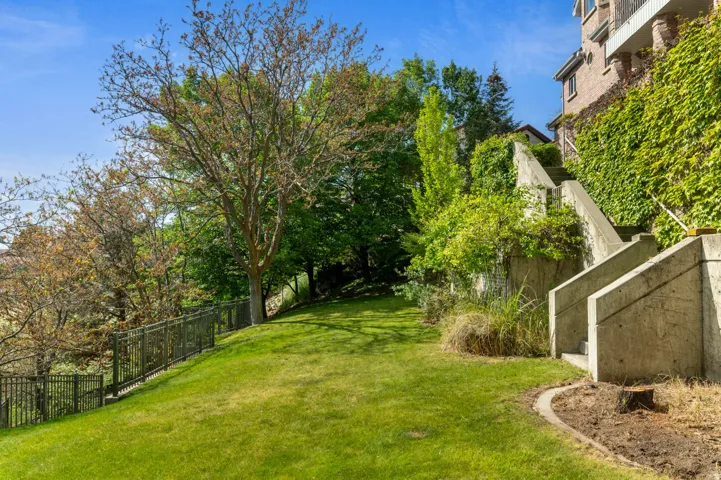 Expansive sloped lawn area bordered by a black metal fence