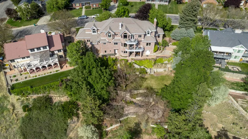 Brick exterior residence featuring multiple balconies and a large, sloped, treed property