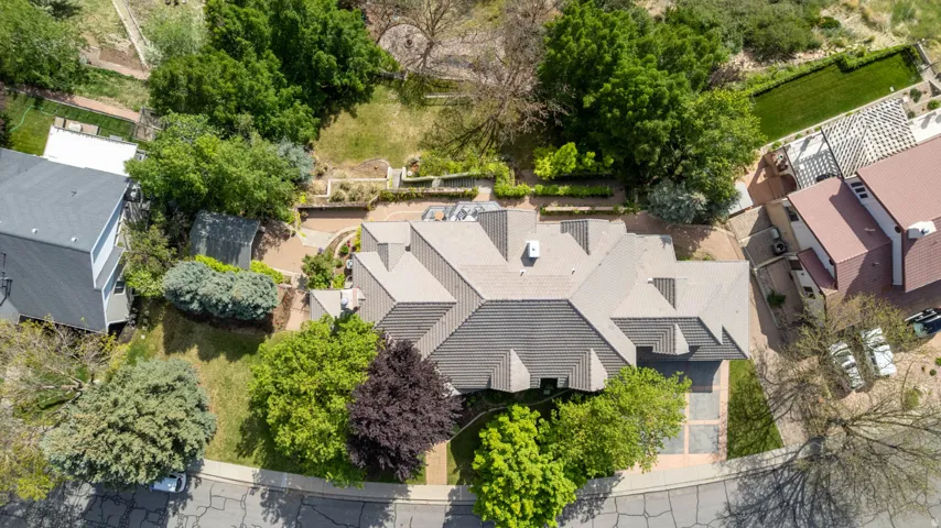 Asymmetrical roofline with multiple gables, surrounded by mature trees and varied landscaping