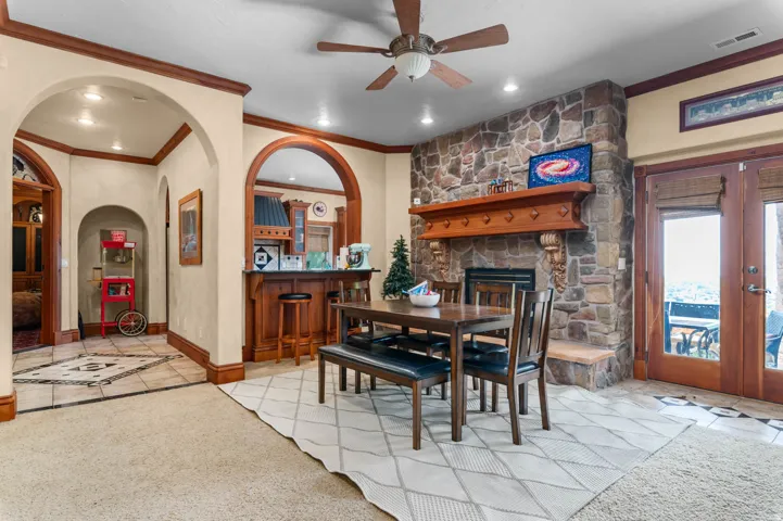 Stone-clad fireplace with a prominent wood mantel, recessed lighting, and wood-finish arched doorways