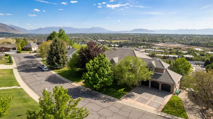 Expansive property with a multi-car garage, mature landscaping, and mountain backdrops