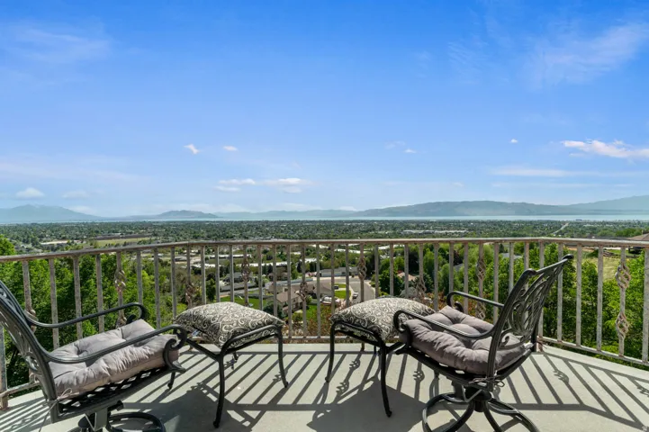 Expansive balcony off primary bedroom suite offering elevated panoramic scenery, including distant mountains and a body of water.