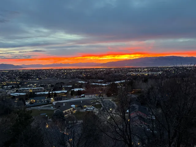 Expansive city lights with a vibrant sunset and distant mountains