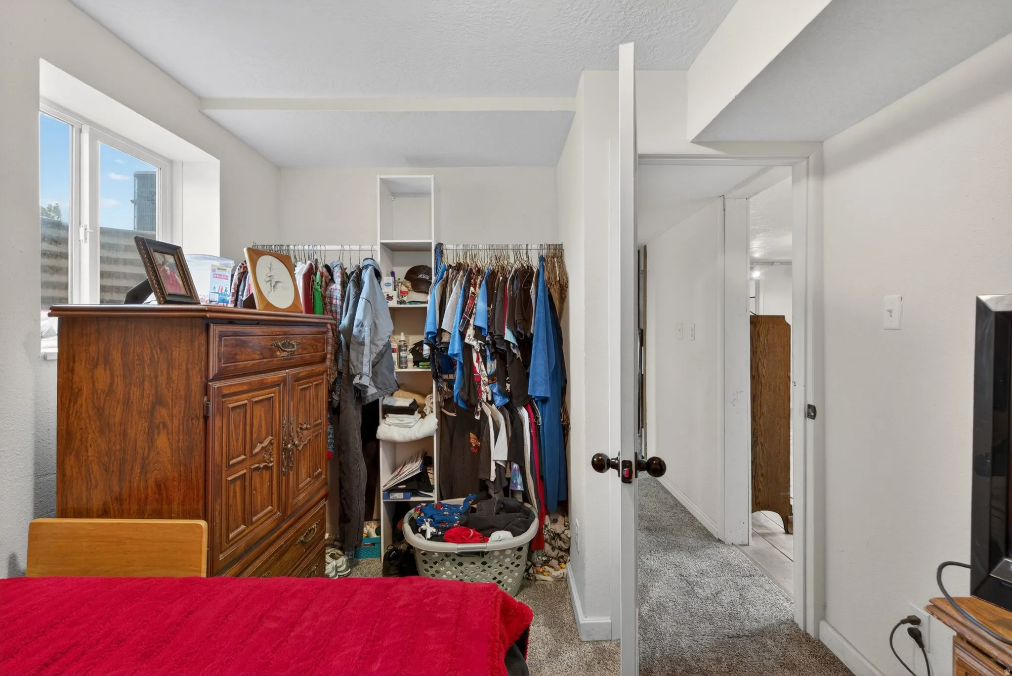 Bedroom featuring a double-paned window, neutral wall paint, and a built-in closet system with open shelving and hanging rods
