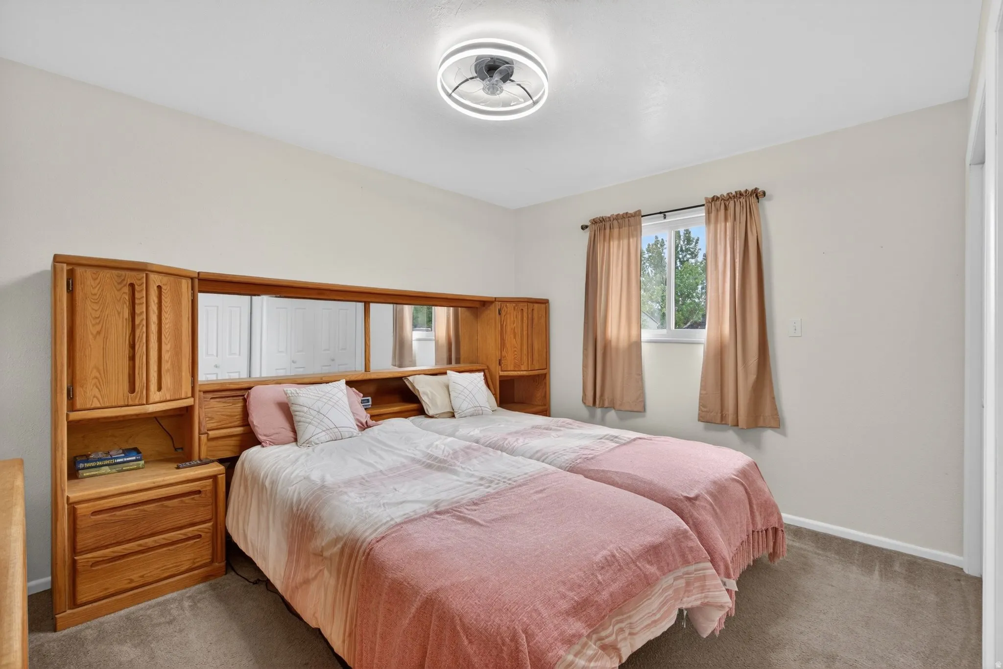 Light-filled room featuring a built-in wood-finish storage headboard with integrated shelving and mirrored accents