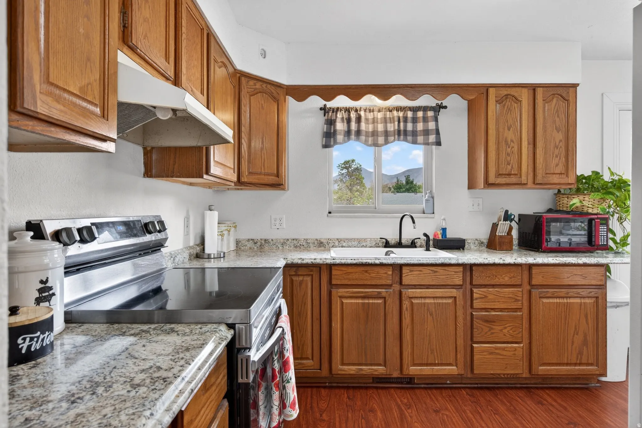 Kitchen featuring wood cabinetry, light-toned speckled countertops, and wood-finish flooring