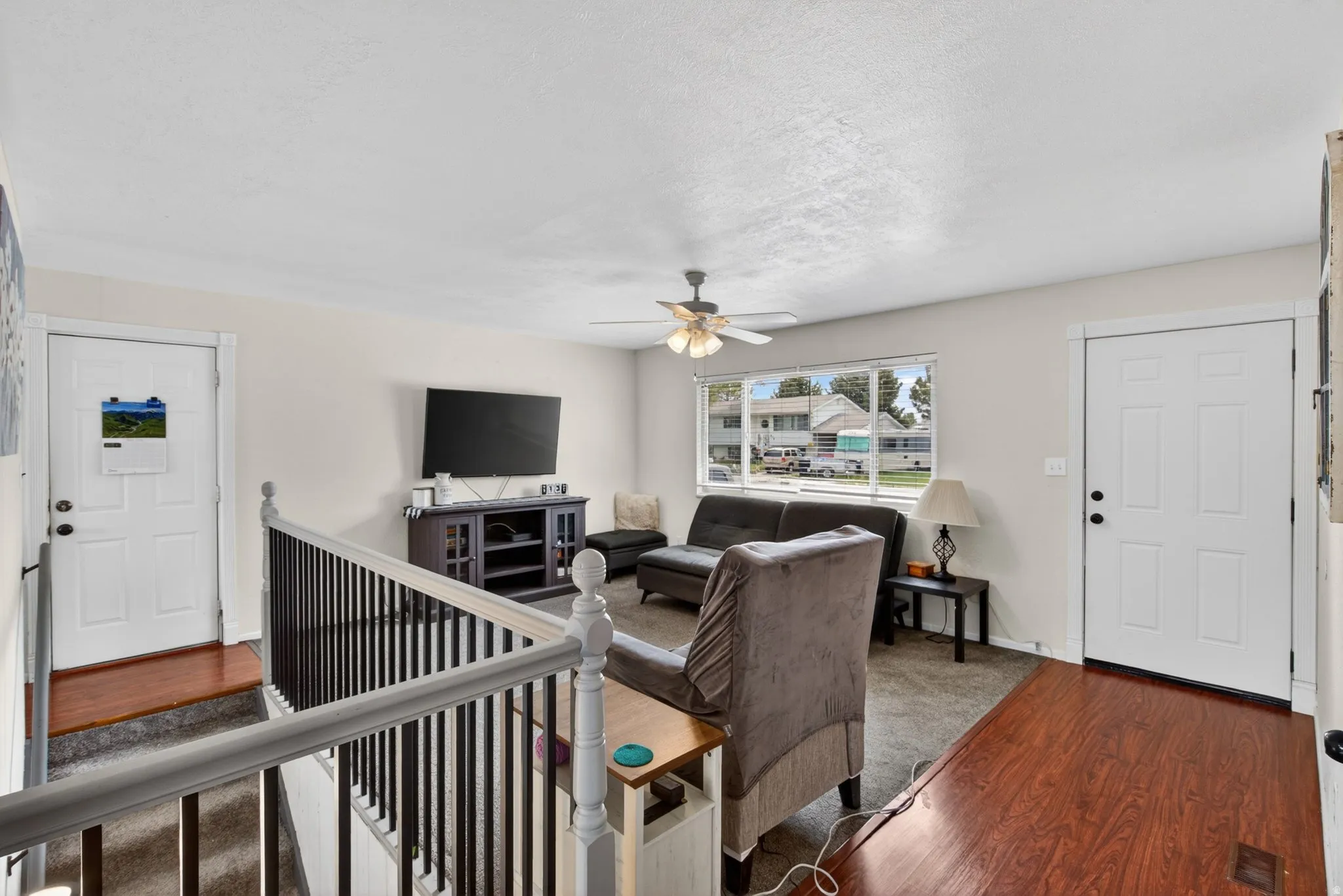 Living area featuring light-colored walls and a ceiling fan