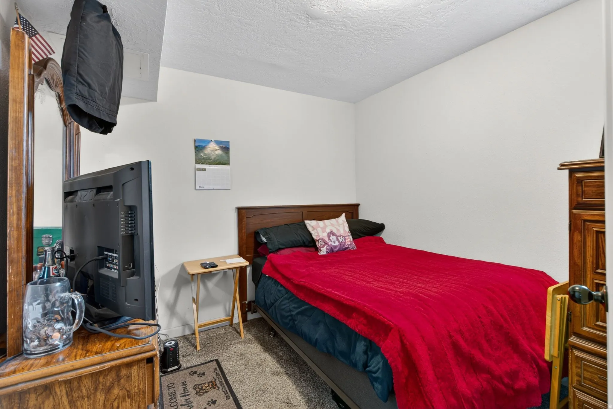 Bedroom featuring wood-finish headboard, white walls, and carpet flooring