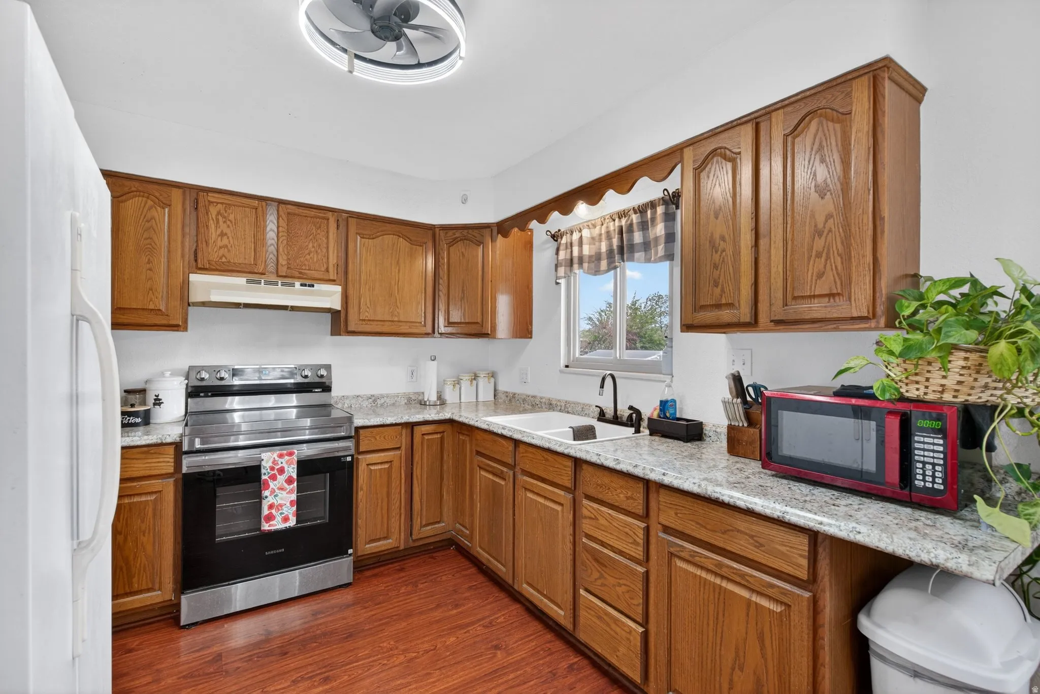 Kitchen featuring wood-finish cabinetry, speckled countertops, and wood-finish flooring