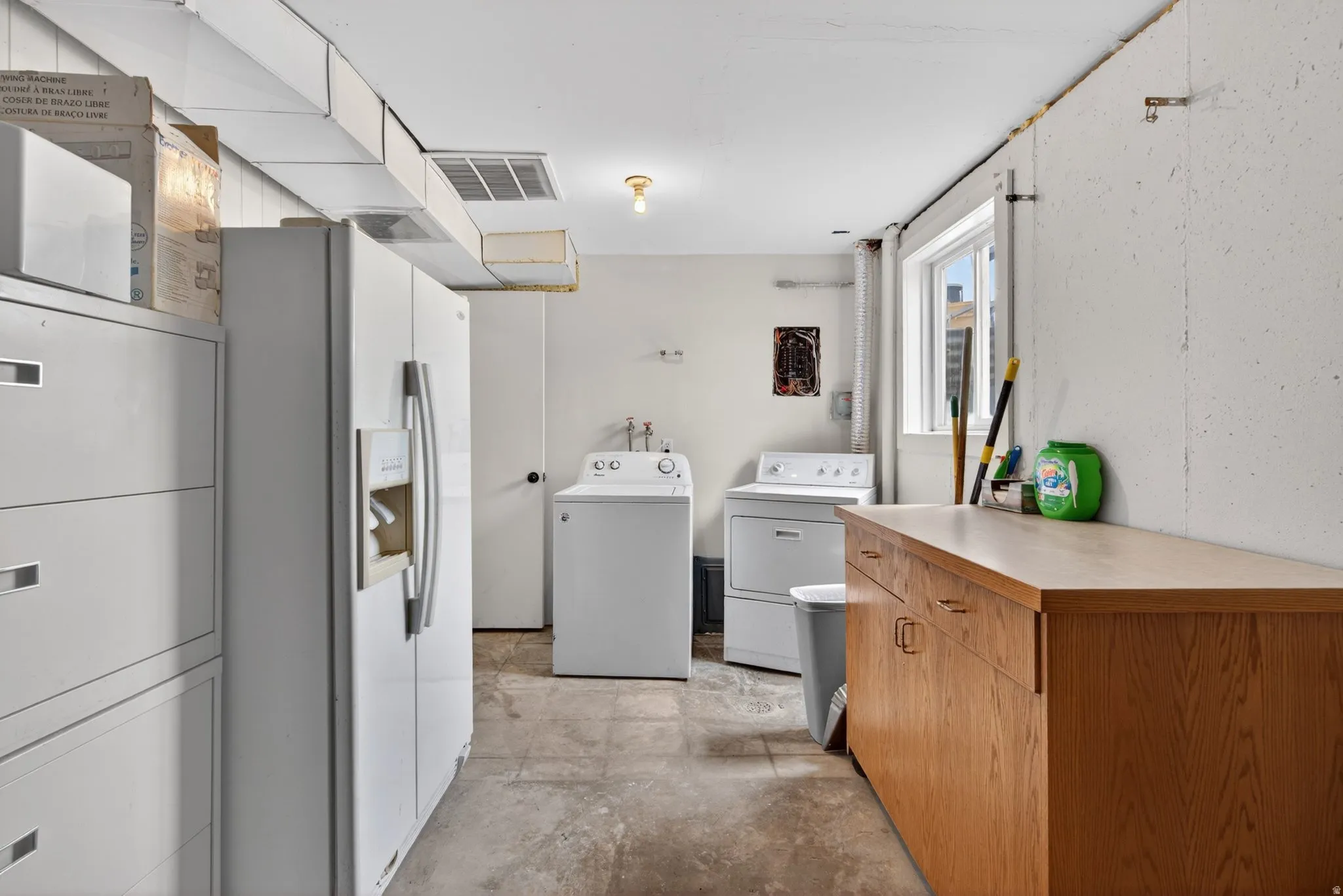 Laundry area with a window, tile flooring, wood-finish cabinetry, and exposed ductwork