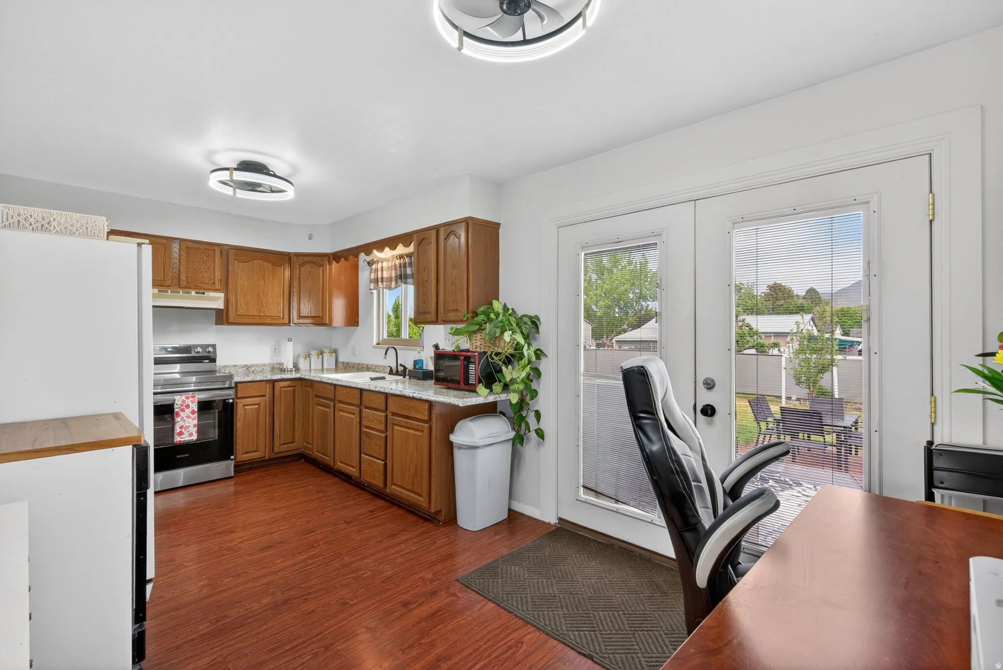 Kitchen featuring wood-finish flooring, wood cabinetry, stone countertops, and stainless steel appliances