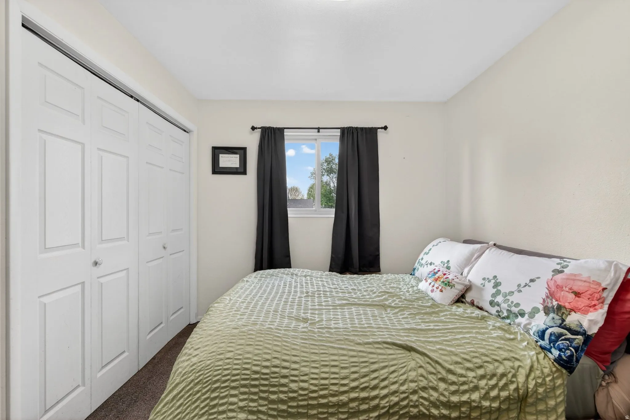 Bedroom featuring a window with natural light, neutral wall paint, bi-fold closet doors, and carpet flooring