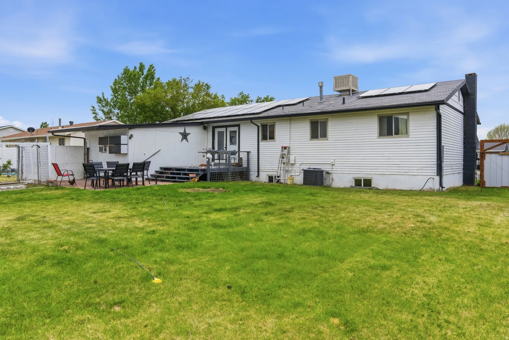 Expansive backyard featuring a manicured lawn, a paved patio area, and an outdoor deck with stairs