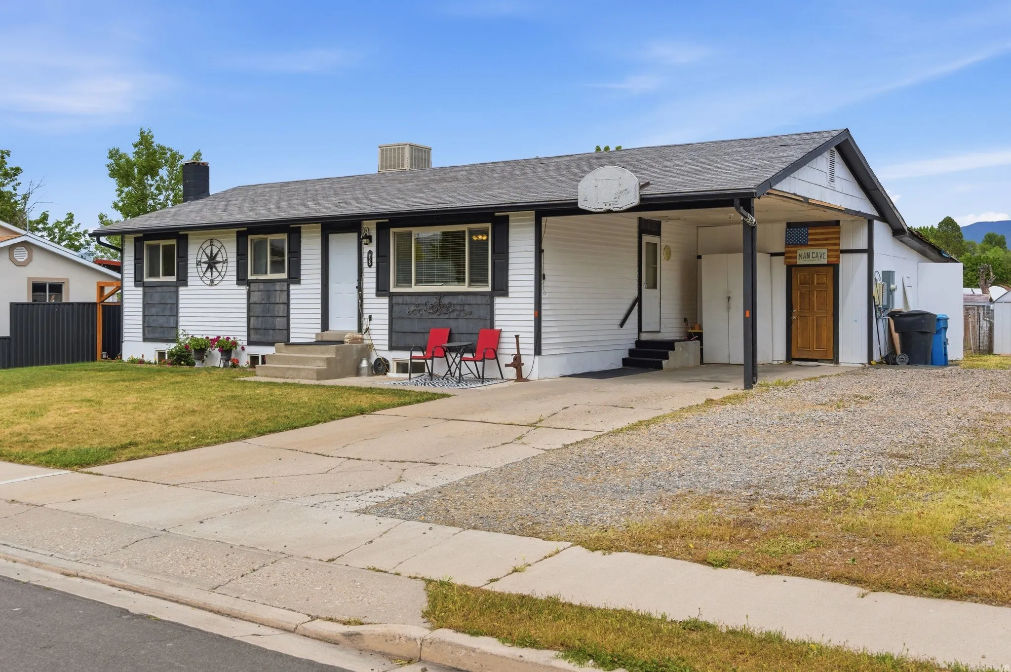 White siding exterior with black trim, a dark gray shingle roof, and a covered carport