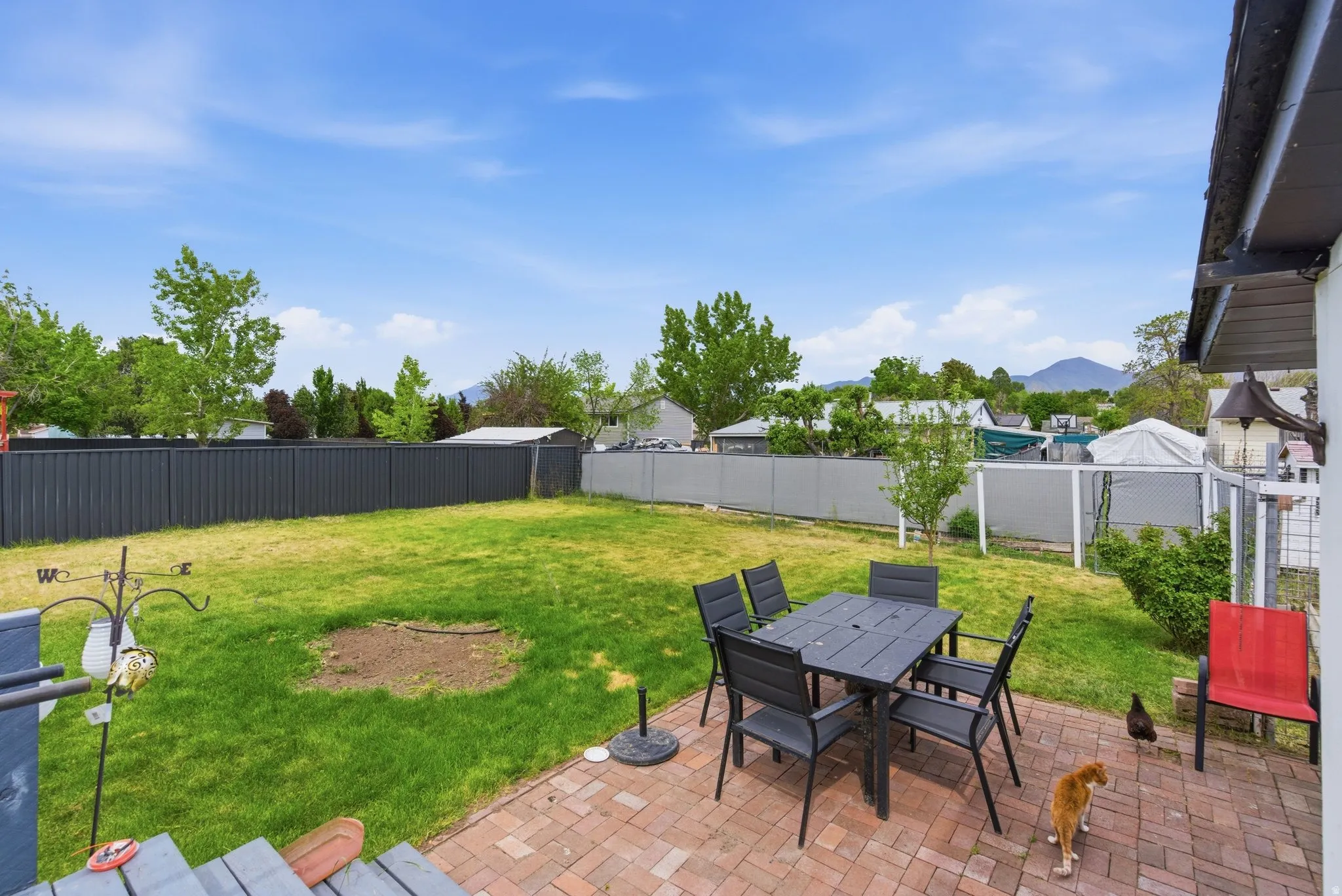 Expansive fenced backyard featuring a brick paver patio, a substantial lawn area, and mature perimeter trees