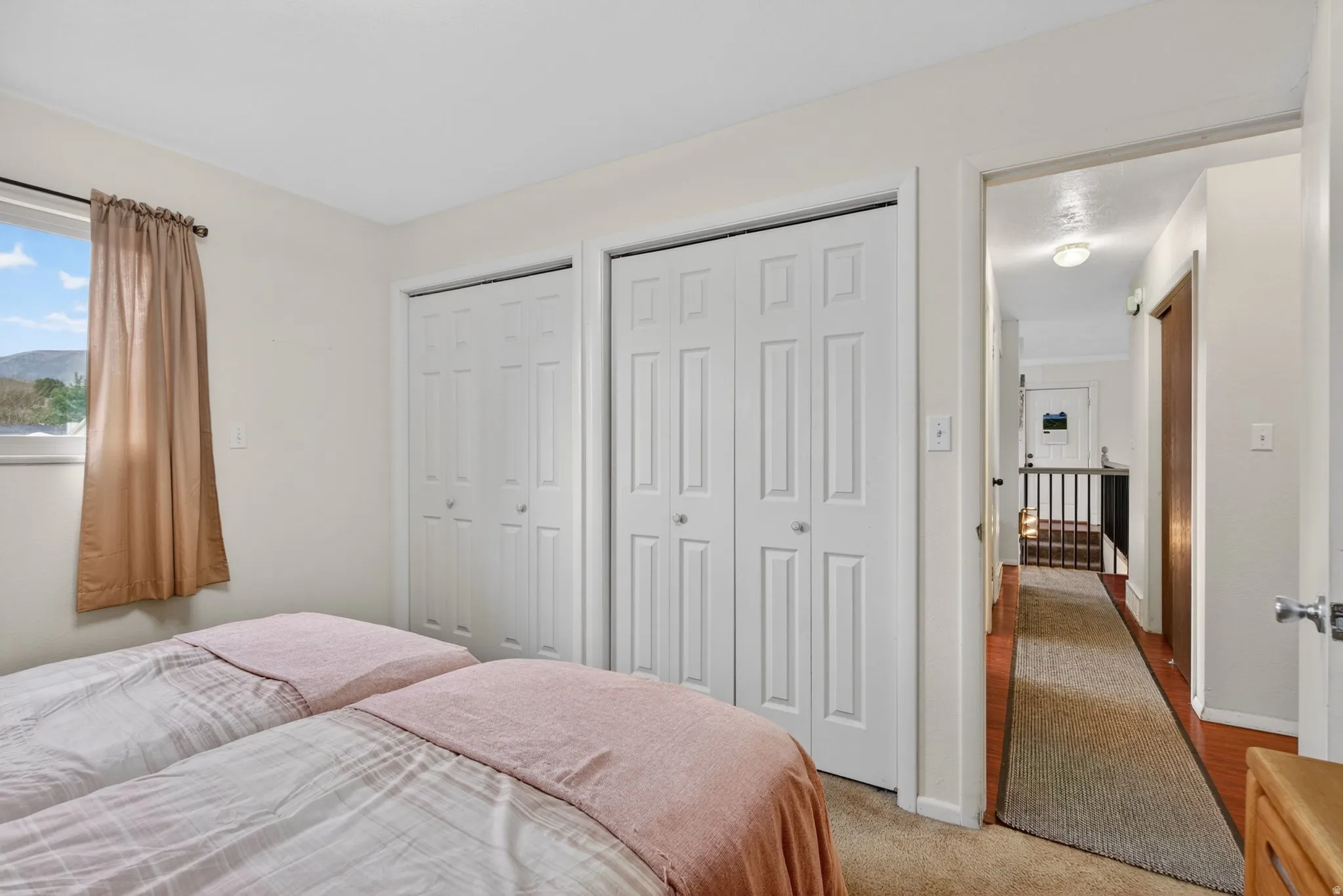 Bedroom featuring two paneled bi-fold closet doors, a single window, and neutral wall paint