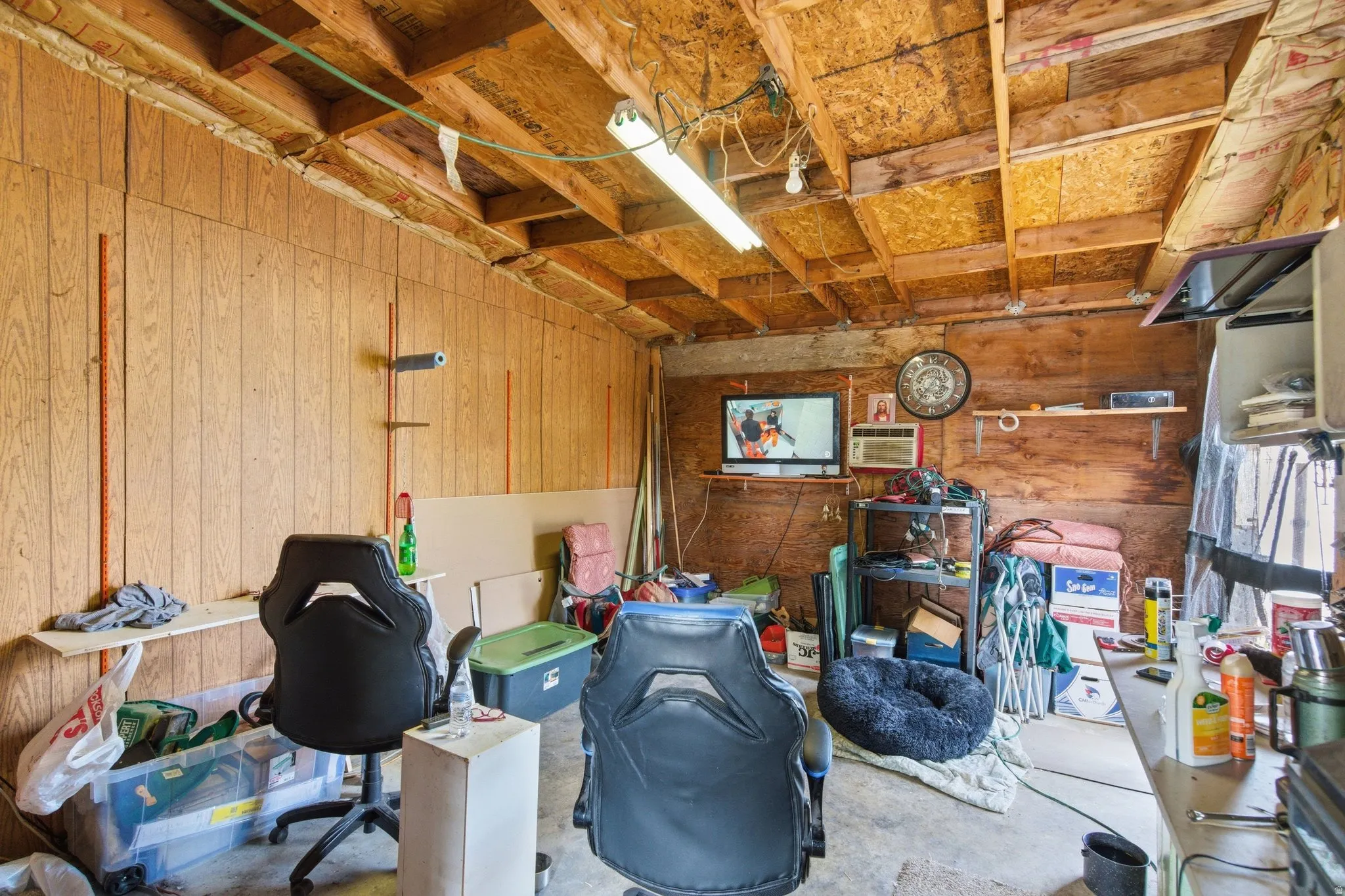 Wood-paneled interior space behind carport. Can be used as a workshop, storage, etc. Has Electricity.