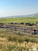 Expansive agricultural landscape featuring a split-rail fence, cultivated fields, and distant mountains