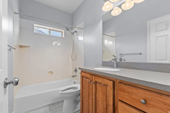 Bathroom featuring a tub/shower combination, transom window, wood-finish vanity with a single basin sink, and a large mirror
