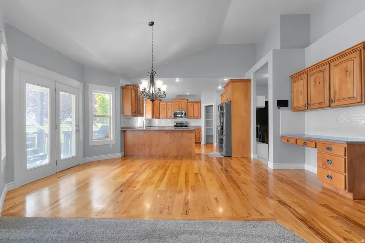 Open-concept living area with vaulted ceilings, wood-finish flooring, and a kitchen featuring wood cabinetry
