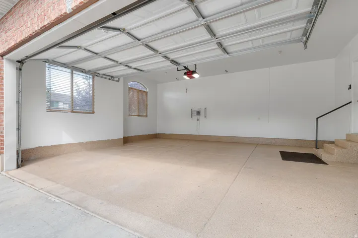 Spacious garage featuring a durable epoxy floor coating, white painted walls, and an arched window