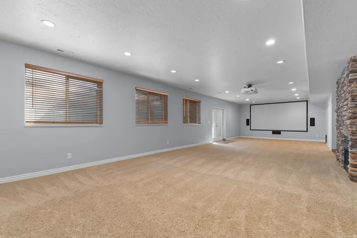 Spacious entertainment room featuring recessed lighting, a large projection screen, and an integrated projector