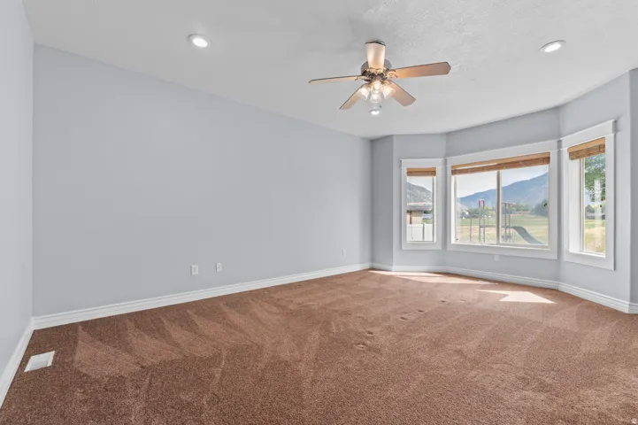 Expansive room featuring a bay window with mountain scenery, recessed lighting, and a ceiling fan