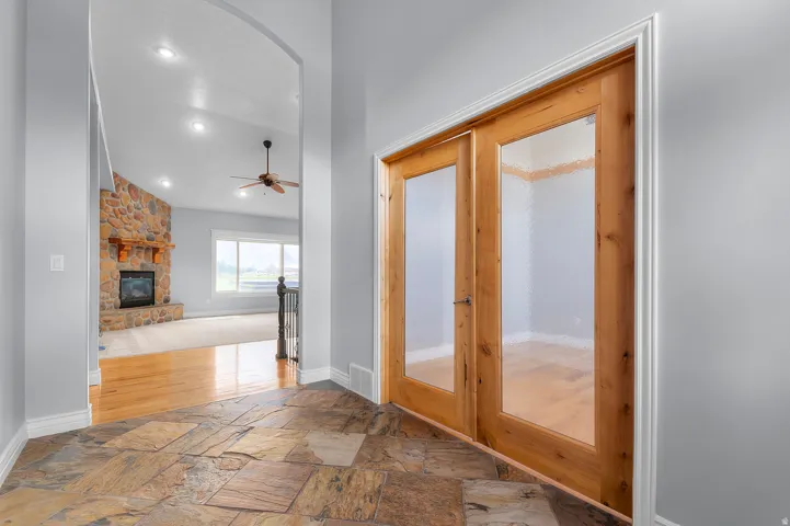 Entryway featuring natural stone tile flooring and light wood double doors with frosted glass panels
