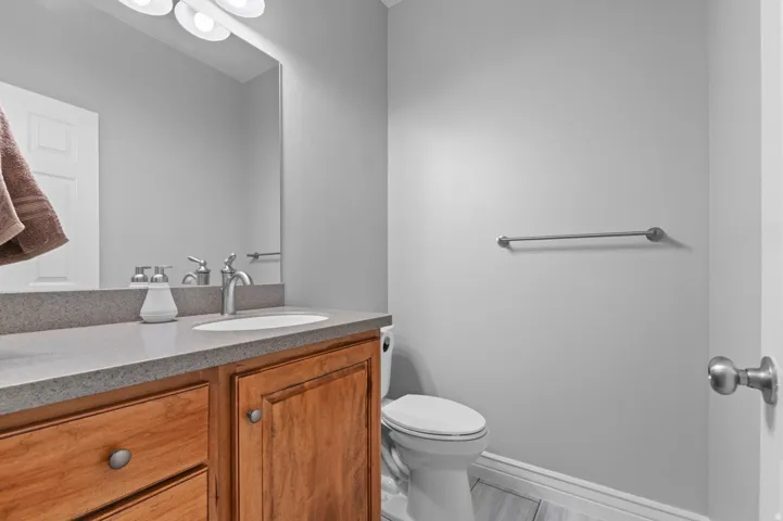 Bathroom featuring a wood-finish vanity with a light-toned countertop, an undermount sink, and a chrome faucet