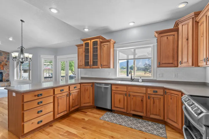 Spacious kitchen featuring light wood cabinetry with display uppers, stainless steel appliances, and a light-toned countertop