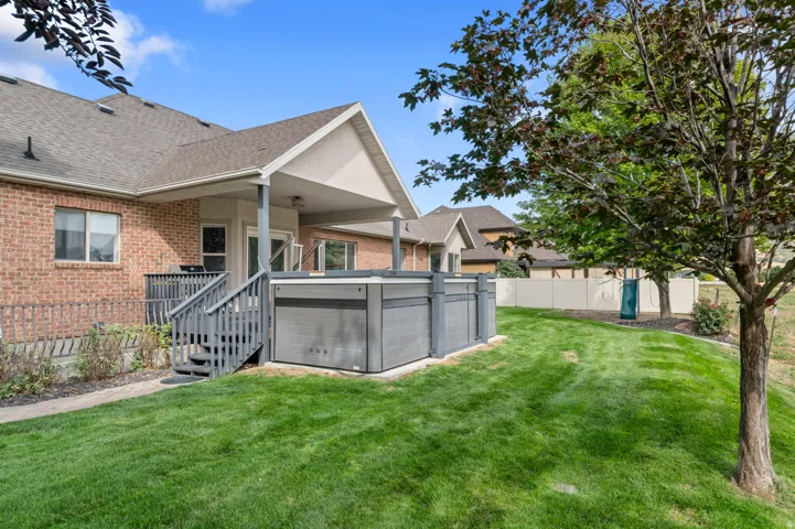 Expansive backyard featuring a manicured lawn, covered patio, attached deck, and built-in spa