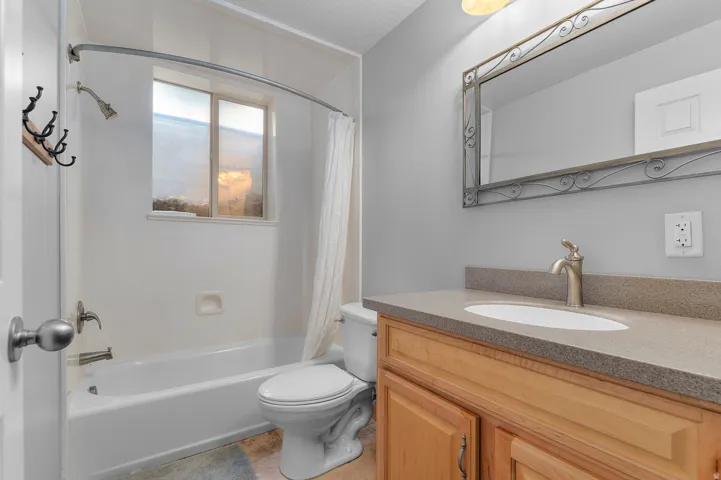 Bathroom featuring a wood-finish vanity with a built-in sink, a neutral-toned countertop, and an ornate framed mirror