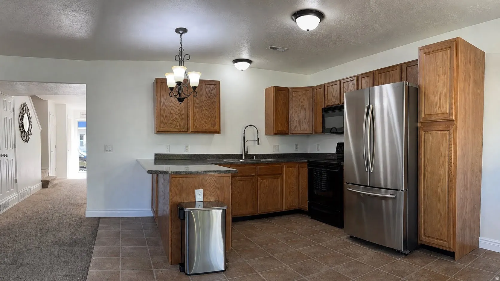 Kitchen featuring wood-finish cabinetry, stainless steel appliances, and a tiled floor