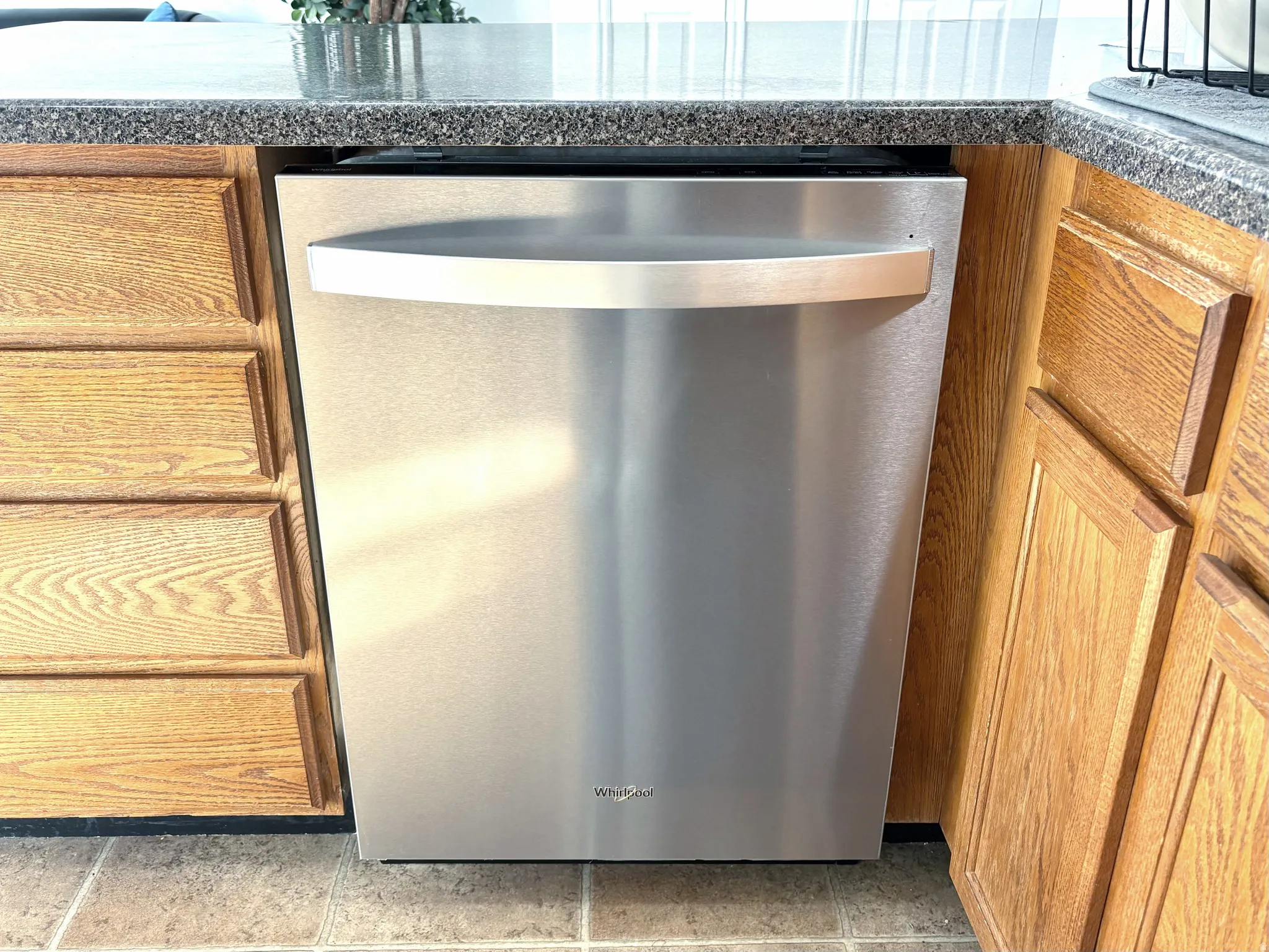 Stainless steel dishwasher integrated within oak cabinetry
