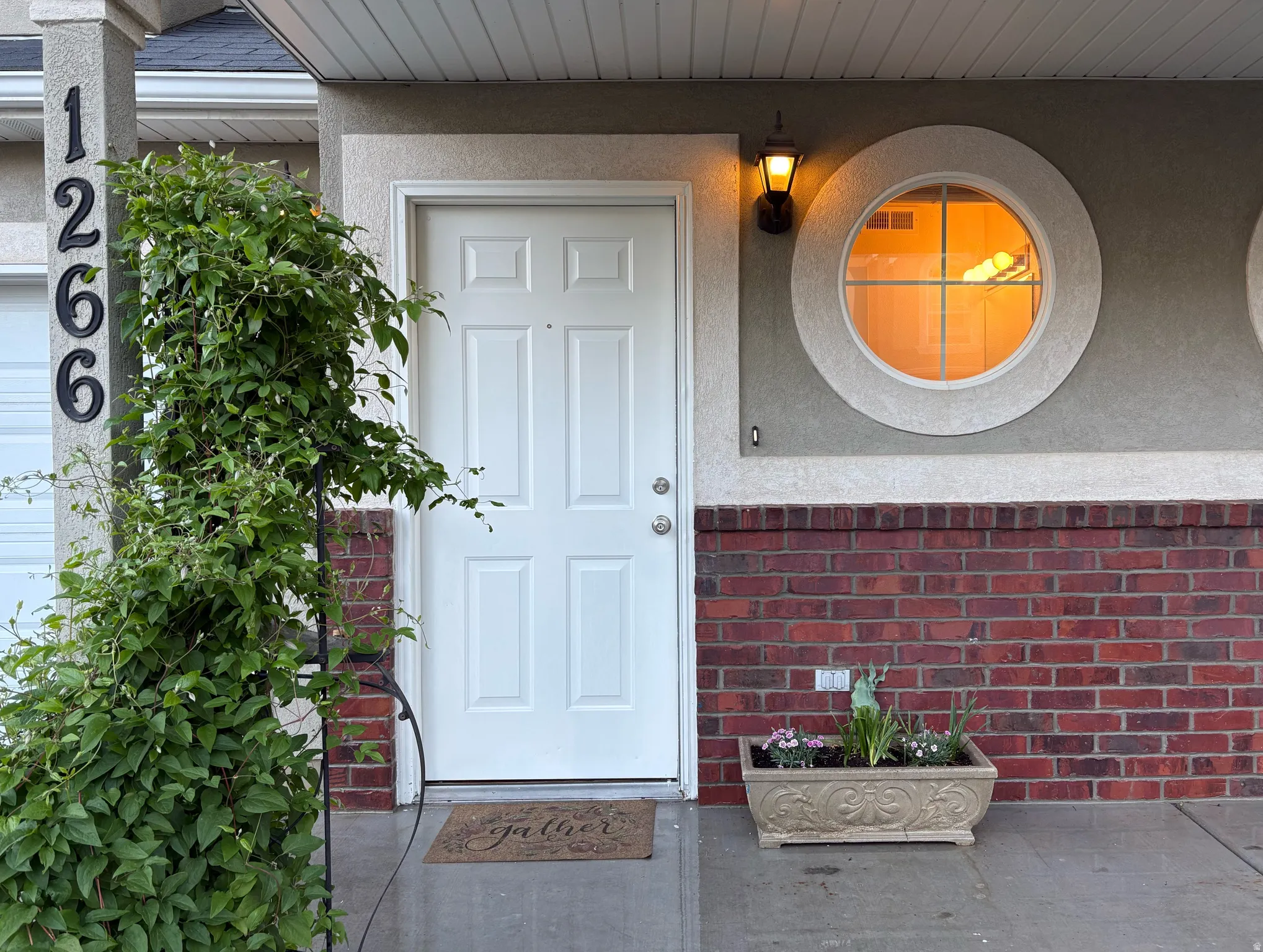 Front entry featuring a paneled door, exterior sconce lighting, and a circular window with grilles