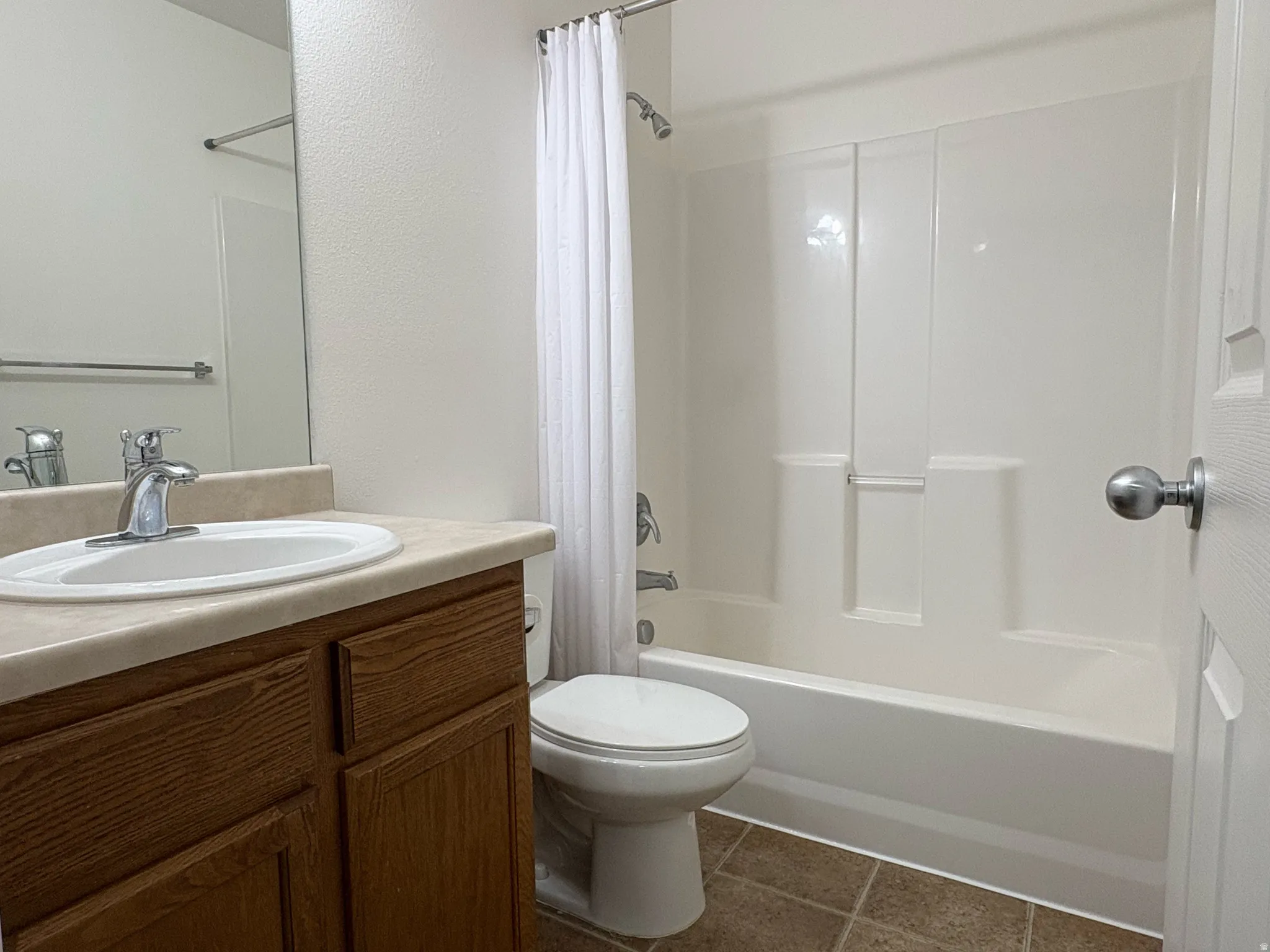 Bathroom featuring a full tub/shower combination, a vanity with a light-toned countertop and integrated sink, a large mirror, and wood-finish cabinetry