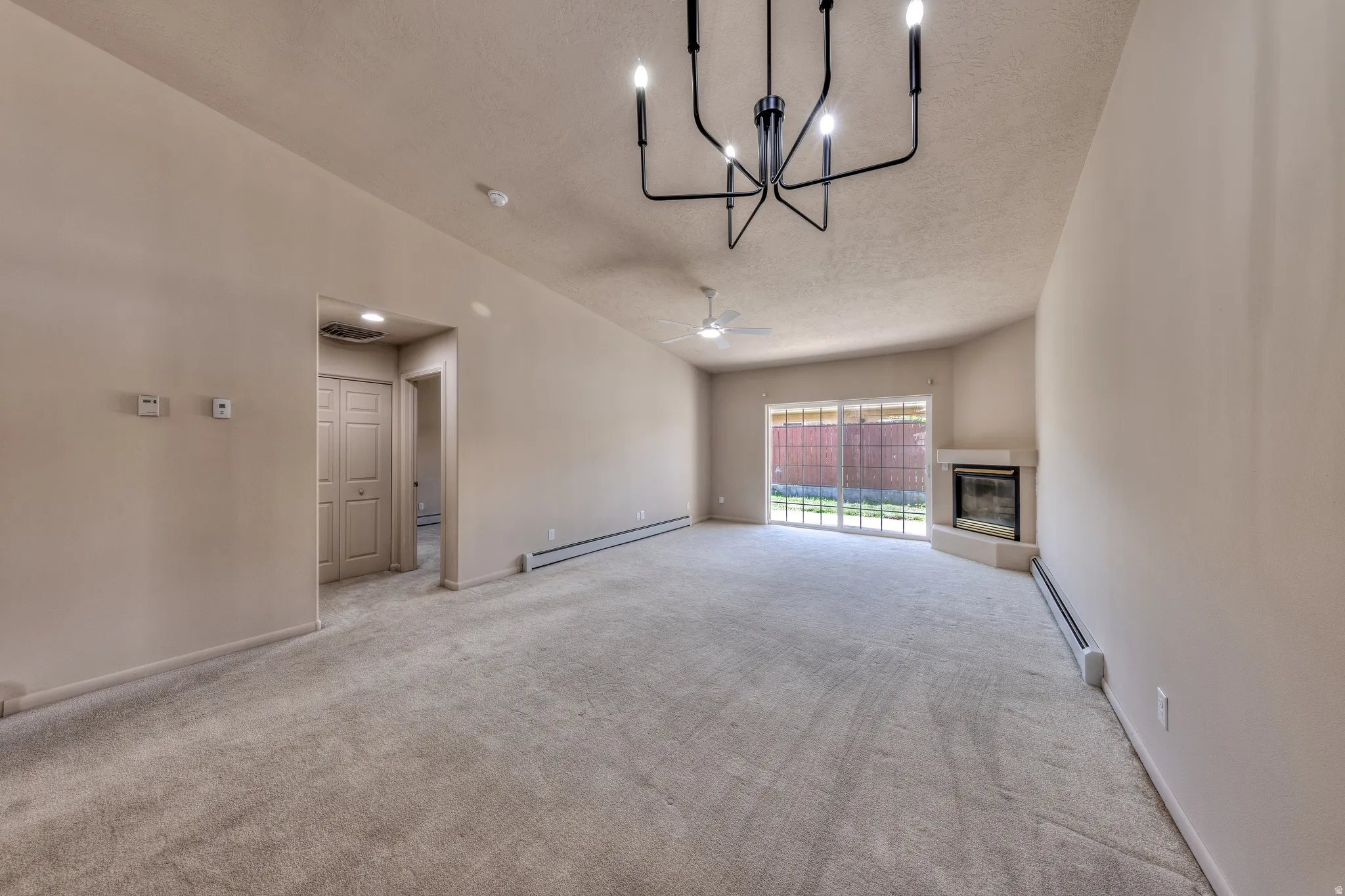 Spacious living area featuring neutral carpeting, a corner fireplace, and sliding glass doors to the exterior