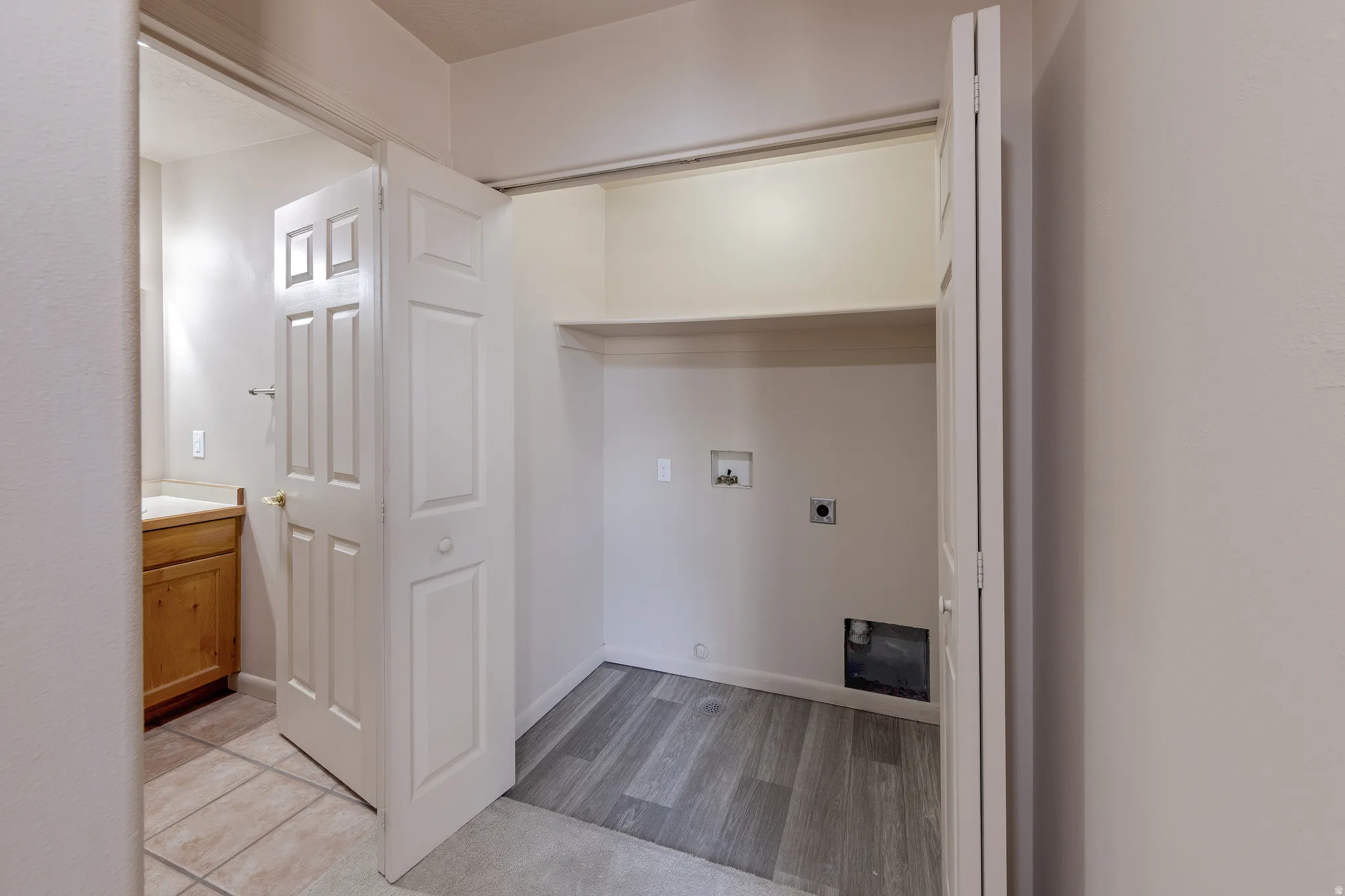 Dedicated laundry alcove with wood-finish flooring and integrated shelving