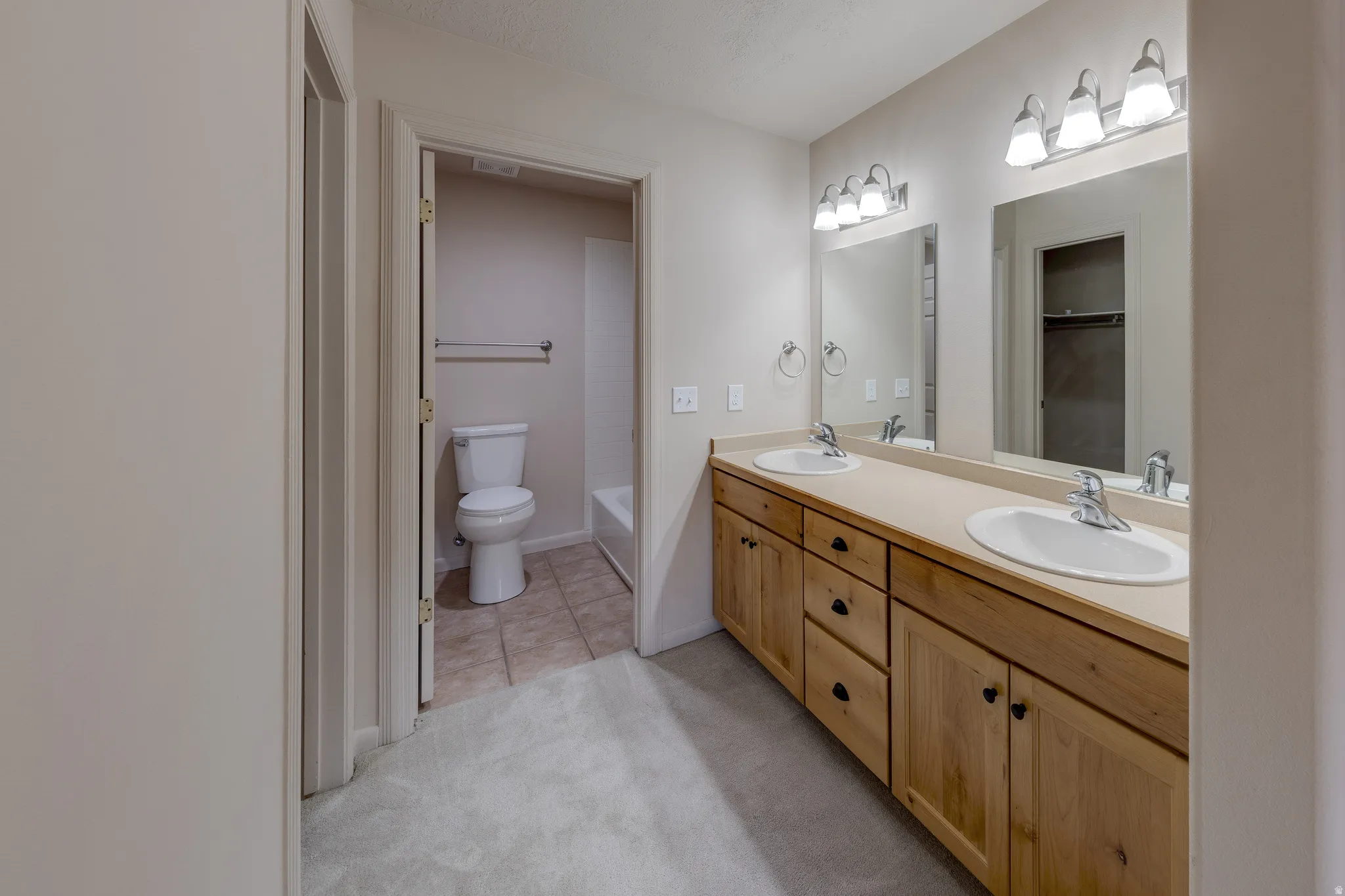 Dual vanity with light wood cabinetry and integrated sinks