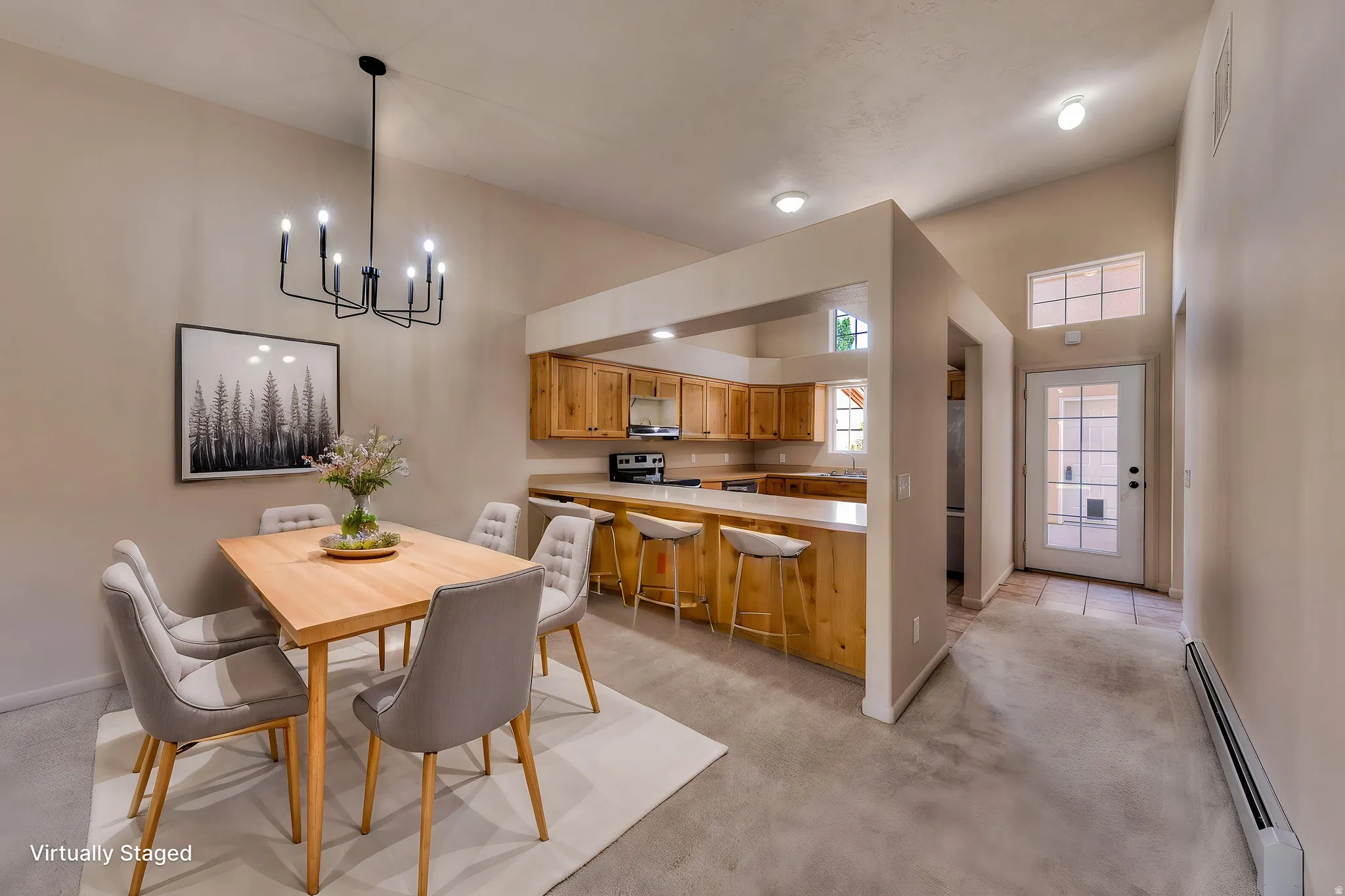 Vaulted ceiling dining area featuring a modern black chandelier, wood-finish flooring, and direct access to the kitchen