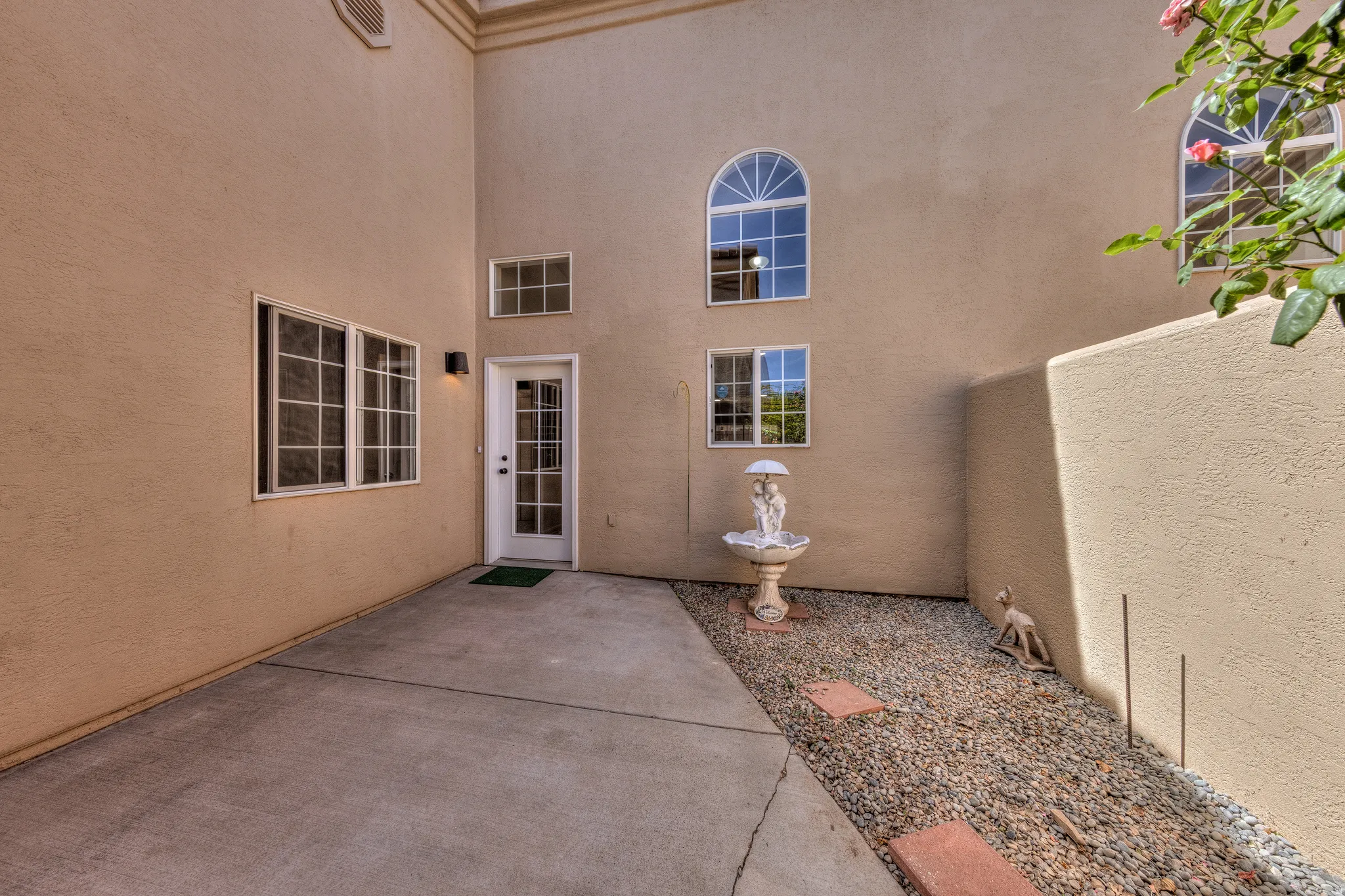 Exterior patio area featuring textured stucco walls and varied window styles