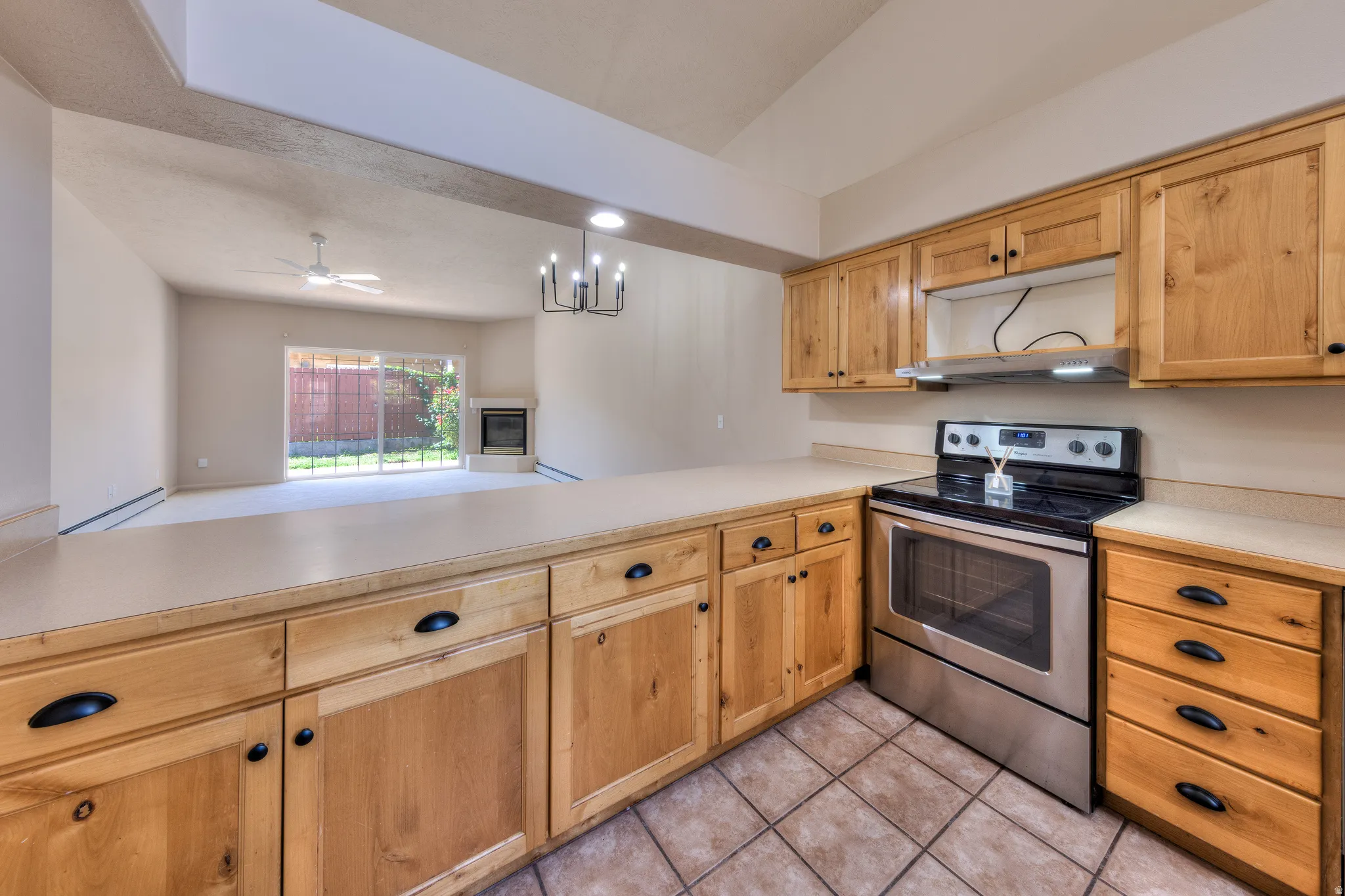 Kitchen featuring natural wood cabinetry with black hardware, light-toned countertops, and a stainless steel oven range