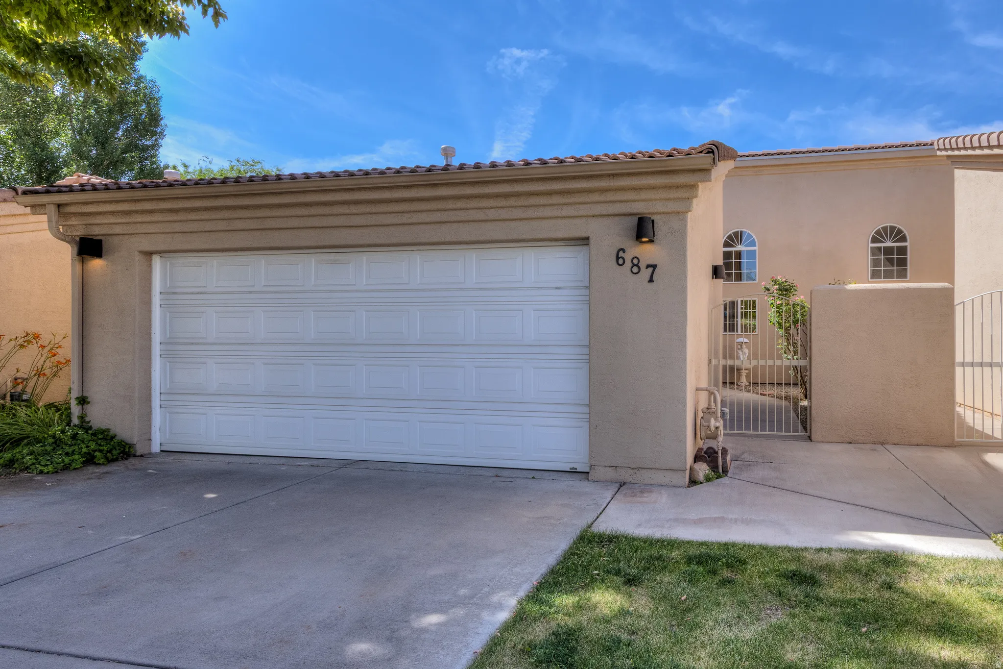Stucco exterior with a two-car garage, tile roof, and arched windows