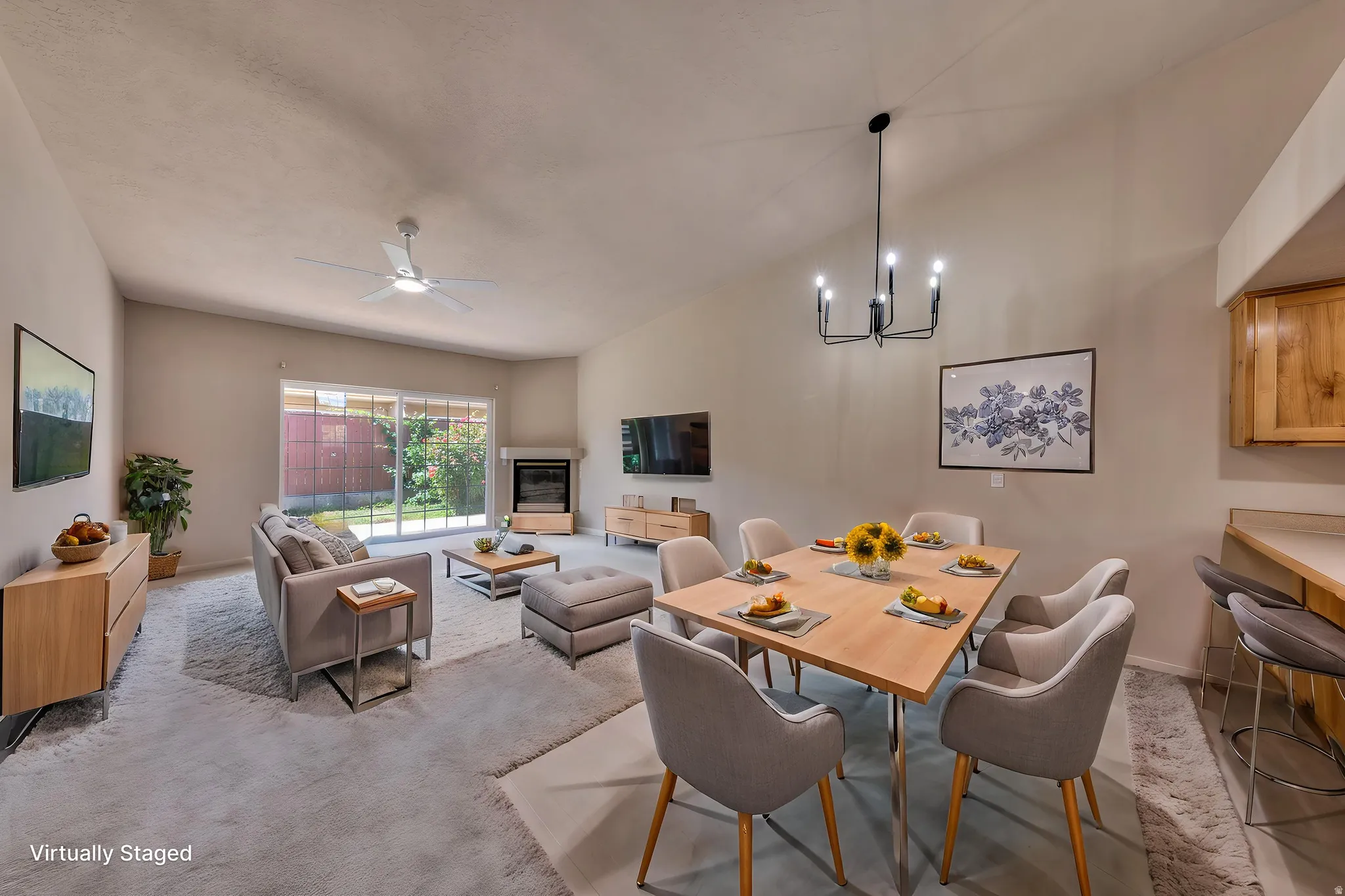 Open-concept living and dining area featuring a vaulted ceiling with a ceiling fan, sliding glass door to the exterior, and a built-in fireplace