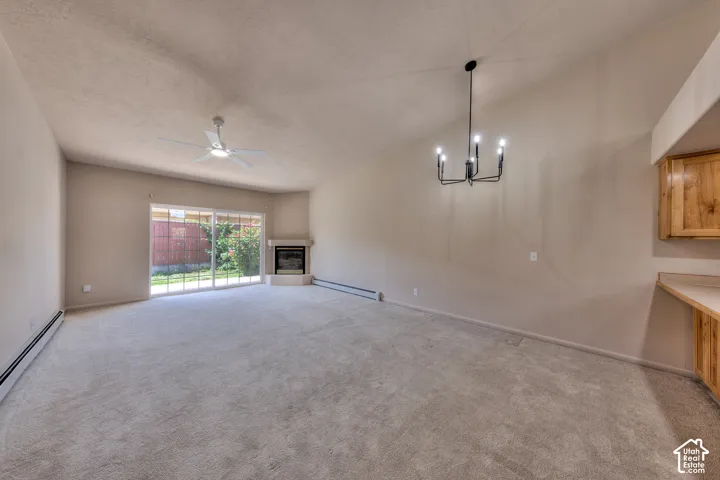Spacious interior featuring vaulted ceilings, light-toned carpeting, a corner fireplace, and a sliding glass door to exterior