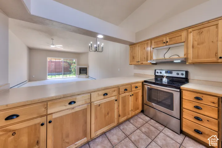 Kitchen featuring natural wood cabinetry with black hardware, light-toned countertops, and a stainless steel oven range