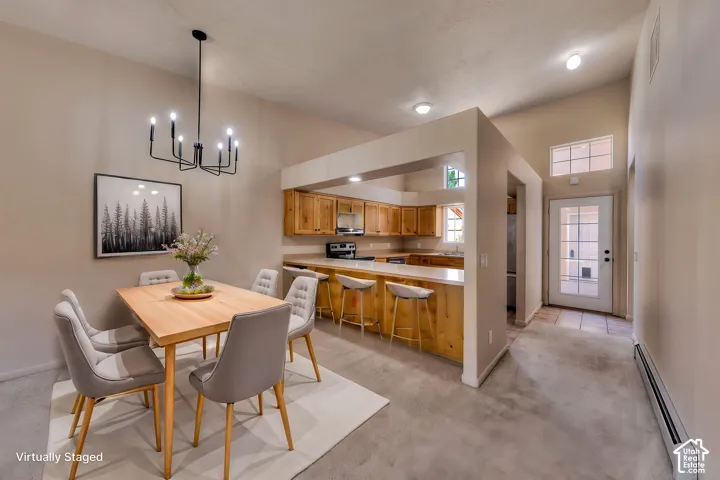 Vaulted ceiling dining area featuring a modern black chandelier, wood-finish flooring, and direct access to the kitchen