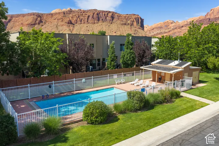 Community swimming pool with a surrounding fence, adjacent pool house, and a paved sun deck